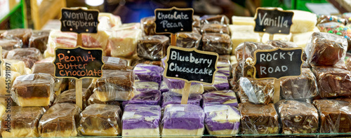 banner of many flavors of fudge wrapped in plastic with signs behind glass photo