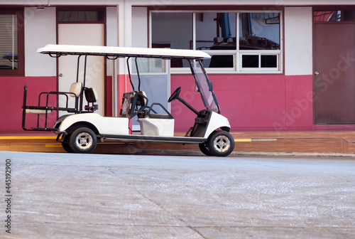 The golf cart is parked near the office part for the electric power charger.