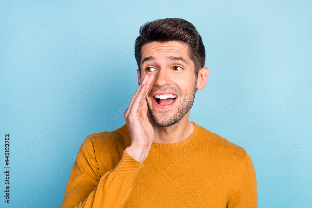 Photo of nice brunet young guy tell secret wear brown shirt isolated on blue color background Photo of nice brunet young guy tell secret wear brown shirt isolated on blue color background