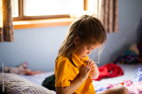 Young school kid getting dressed for school in the morning in her bedroom