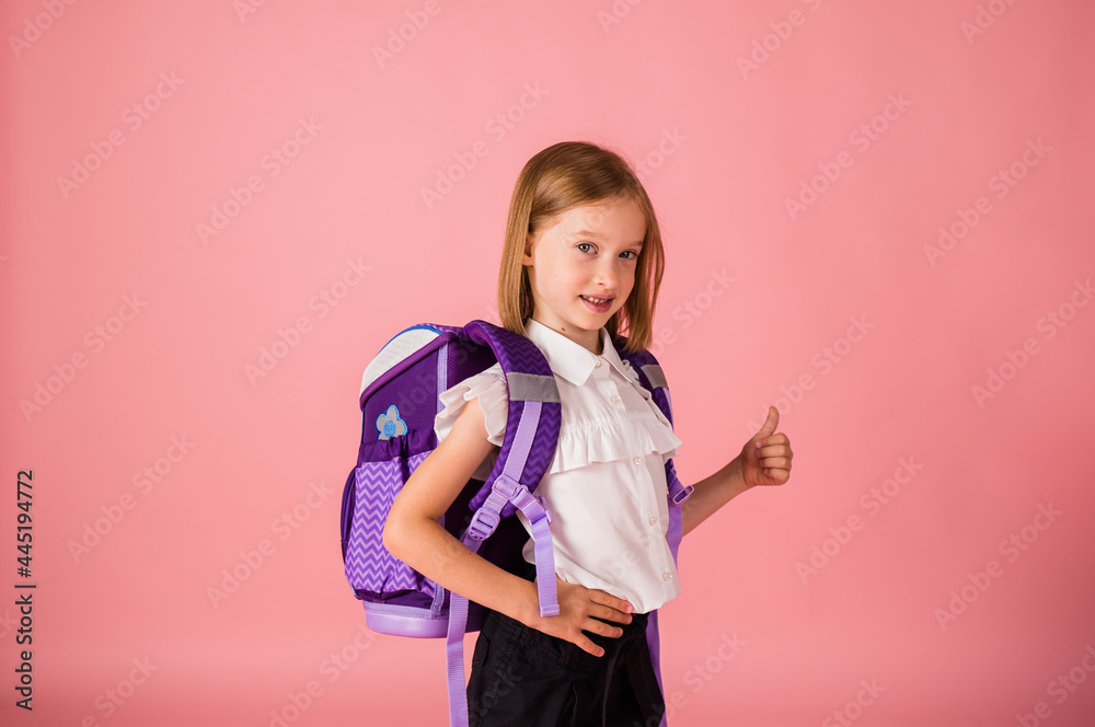 a schoolgirl in uniform and with a backpack stands and shows a class on a pink background with a copy of the space a schoolgirl in uniform and with a backpack stands and shows a class on a pink background with a copy of the space