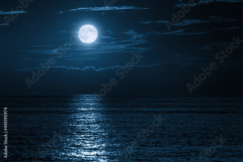 Murais de parede This large full blue moon rises brightly over the cloud bank in this calm ocean