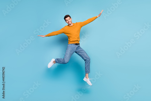 Full length body size view of attractive cheerful lucky guy jumping having fun isolated over bright blue color background