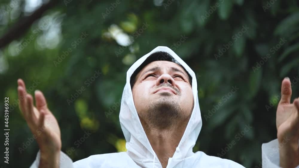 young asian man wearing rainwear under the rain on a background of green trees. young asian man wearing rainwear under the rain on a background of green trees.