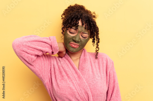 Young mixed race wearing facial mask isolated on yellow background touching back of head, thinking and making a choice. © Asier