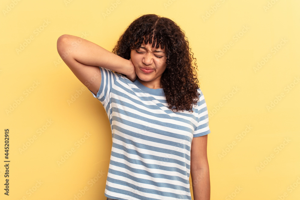 Young mixed race woman isolated on yellow background suffering neck pain due to sedentary lifestyle. Young mixed race woman isolated on yellow background suffering neck pain due to sedentary lifestyle.