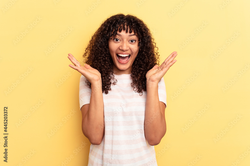 Young mixed race woman isolated on yellow background celebrating a victory or success, he is surprised and shocked. Young mixed race woman isolated on yellow background celebrating a victory or success, he is surprised and shocked.