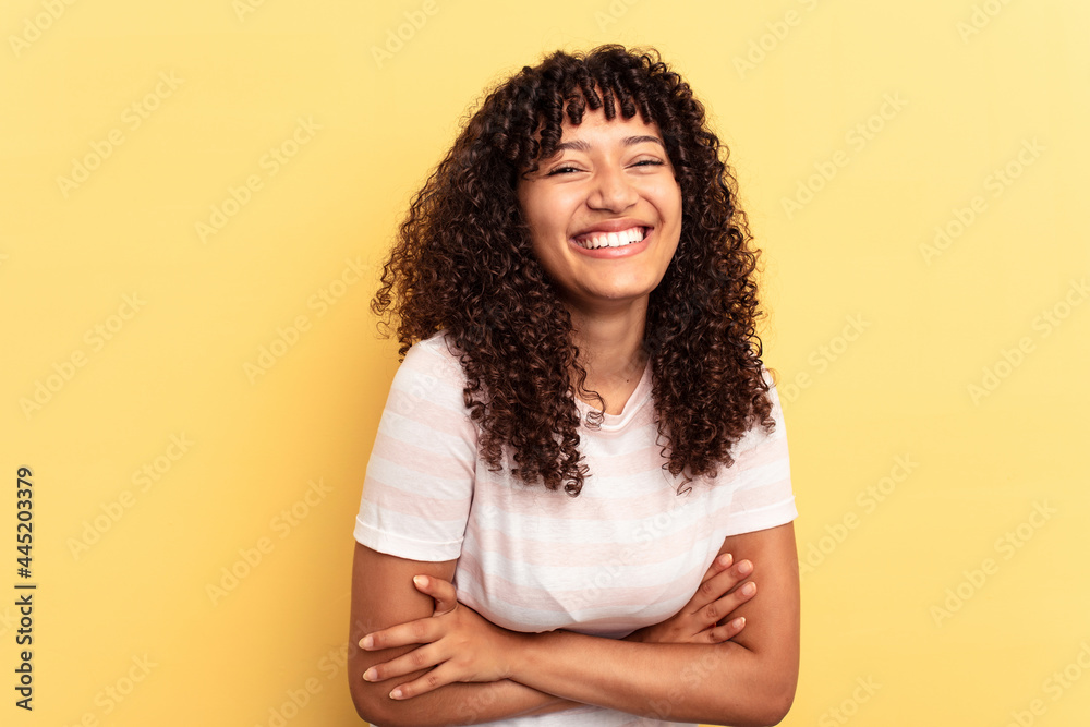 Young mixed race woman isolated on yellow background laughing and having fun. Young mixed race woman isolated on yellow background laughing and having fun.