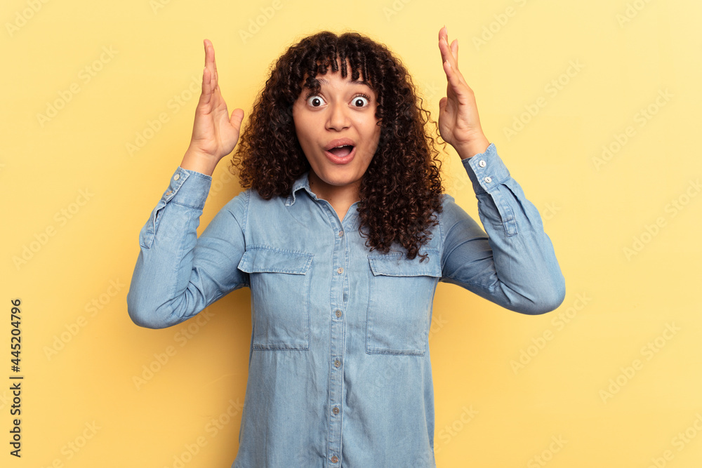Young mixed race woman isolated on yellow background celebrating a victory or success, he is surprised and shocked.