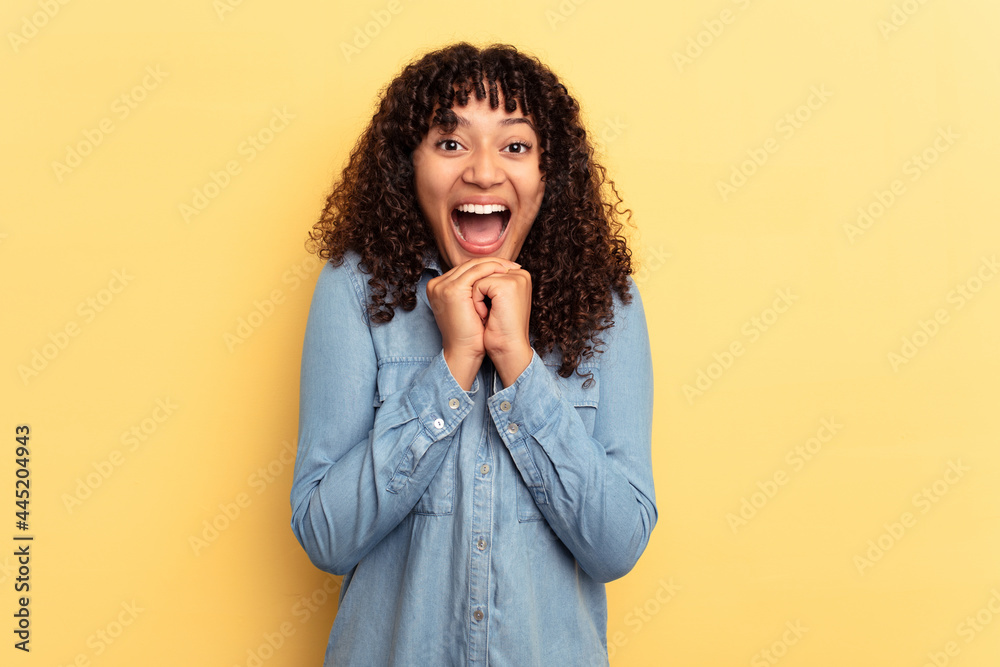 Young mixed race woman isolated on yellow background praying for luck, amazed and opening mouth looking to front. Young mixed race woman isolated on yellow background praying for luck, amazed and opening mouth looking to front.