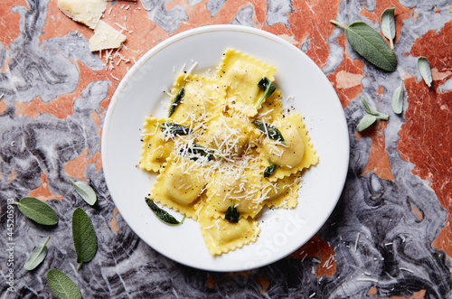 ravioli with butter parmesan and sage dish on a red marble table