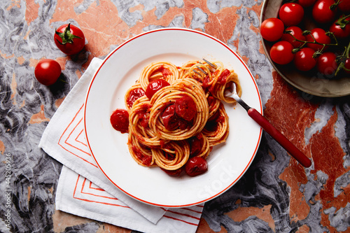 spaghetti and tomato sauce dish on a red marble table photo