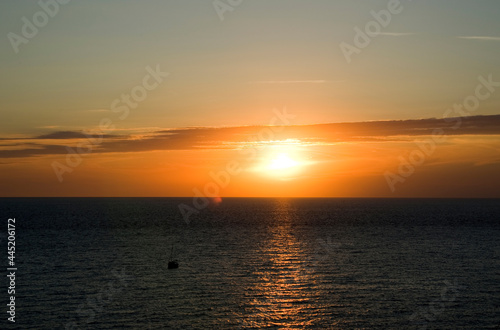 Small sailboat on the high seas at sunset.