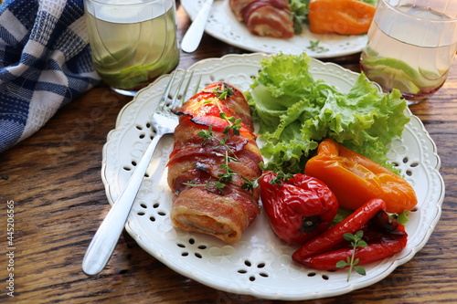 Grilled chicken breast wrapped in bacon served with salad on wooden rustic table . Dinner background