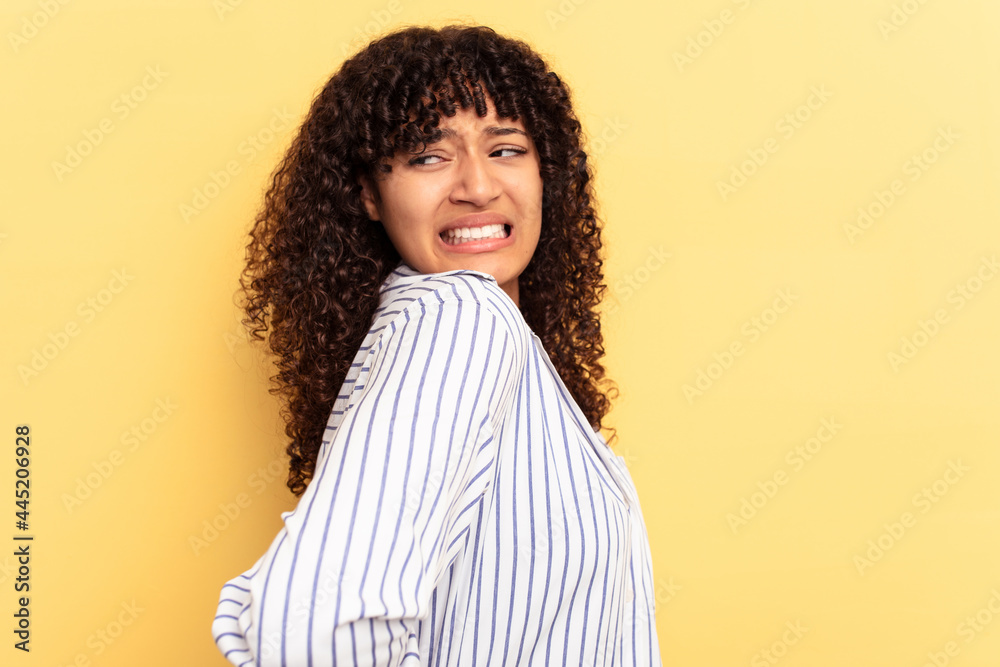 Young mixed race woman isolated on yellow background suffering a back pain. Young mixed race woman isolated on yellow background suffering a back pain.