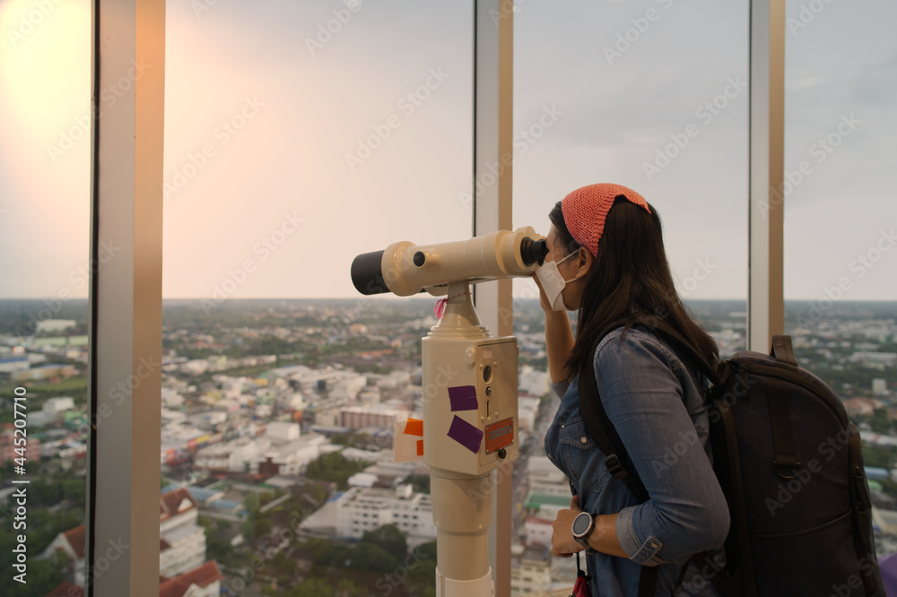 Female tourists looking at binoculars and telescopes in tower travel concept and exploring the surrounding city during summer.