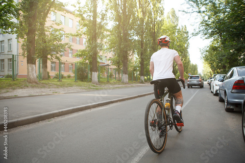 Rear view full length shot of a male cyclist in bike helmet riding bicycle in the city © mad_production