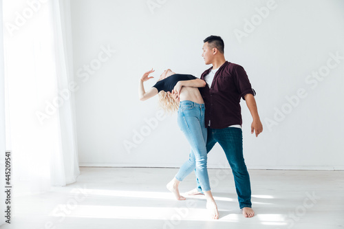 a man and a woman dance bachata music in a white room