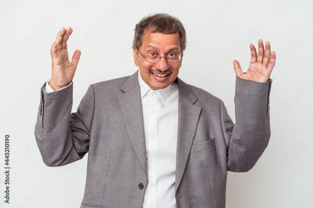 Middle aged indian business man isolated on white background receiving a pleasant surprise, excited and raising hands. Middle aged indian business man isolated on white background receiving a pleasant surprise, excited and raising hands.