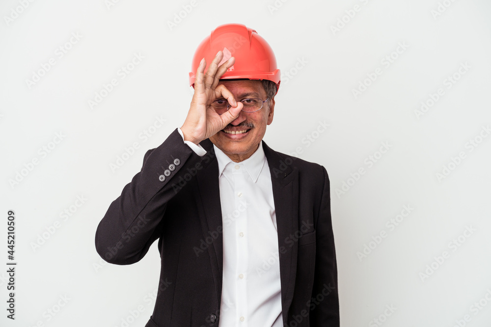 Middle aged indian architect man isolated on white background excited keeping ok gesture on eye. Middle aged indian architect man isolated on white background excited keeping ok gesture on eye.
