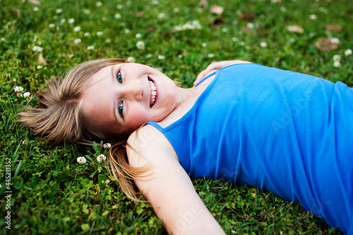 pretty blue-eyed tween girl lying in the grass photo
