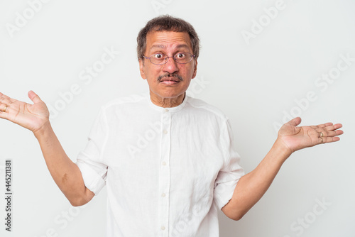 Middle aged indian man isolated on white background confused and doubtful shrugging shoulders to hold a copy space.