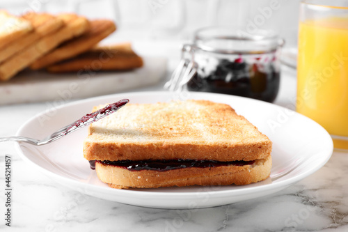 Tasty sandwich with raspberry jam for breakfast on marble table