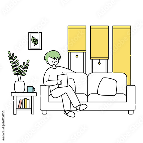 部屋でリラックスしてタブレットを見る男性