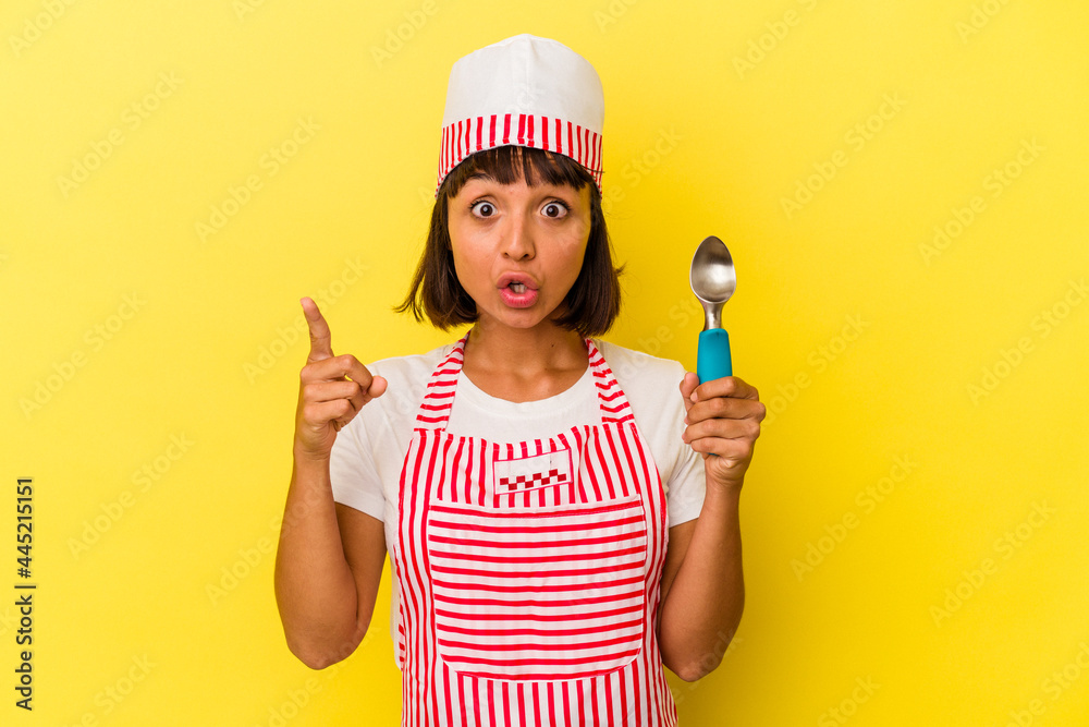 Young mixed race ice cream maker woman holding an ice cream scoop isolated on yellow background having an idea, inspiration concept. Young mixed race ice cream maker woman holding an ice cream scoop isolated on yellow background having an idea, inspiration concept.