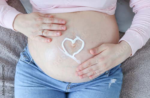 Wallpaper Mural The pregnant woman holds her belly.
A pregnant woman holds her belly with a heart made of moisturizer, top view, close-up. Torontodigital.ca