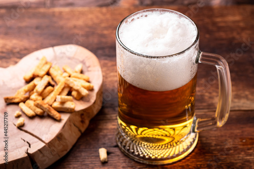 Glass of beer and snacks on a wooden background.