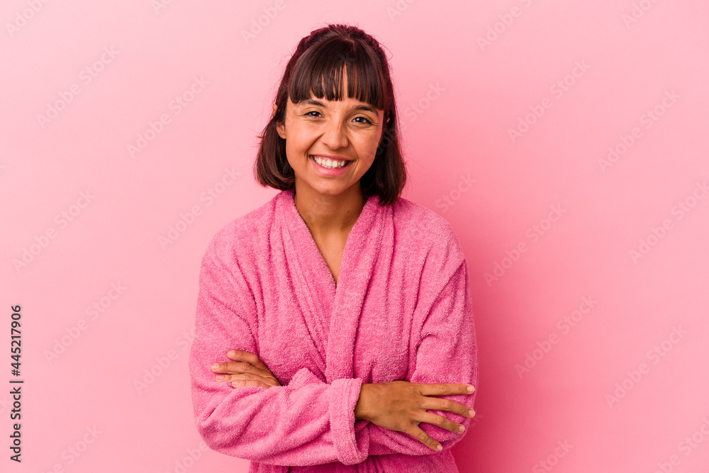 Young mixed race woman wearing a bathrobe isolated on pink background laughing and having fun. Young mixed race woman wearing a bathrobe isolated on pink background laughing and having fun.