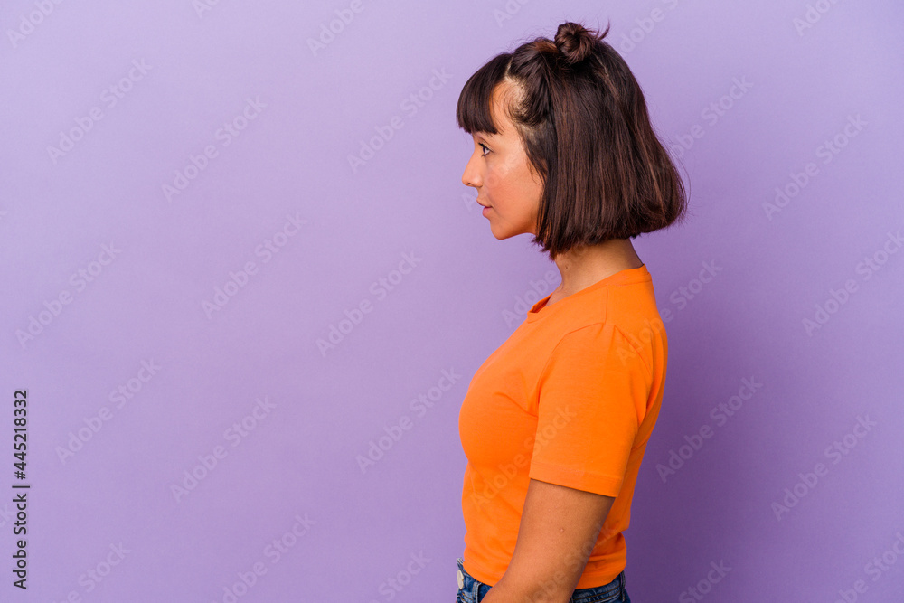 Young mixed race woman isolated on purple background gazing left, sideways pose. Young mixed race woman isolated on purple background gazing left, sideways pose.