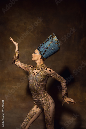 Photography Portrait of young woman in image of Nefertiti in art performance isolated on brown vintage background