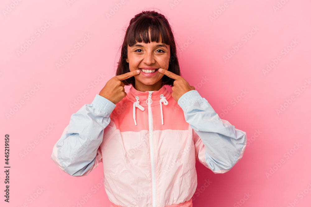 Young mixed race woman isolated on pink background smiles, pointing fingers at mouth. Young mixed race woman isolated on pink background smiles, pointing fingers at mouth.