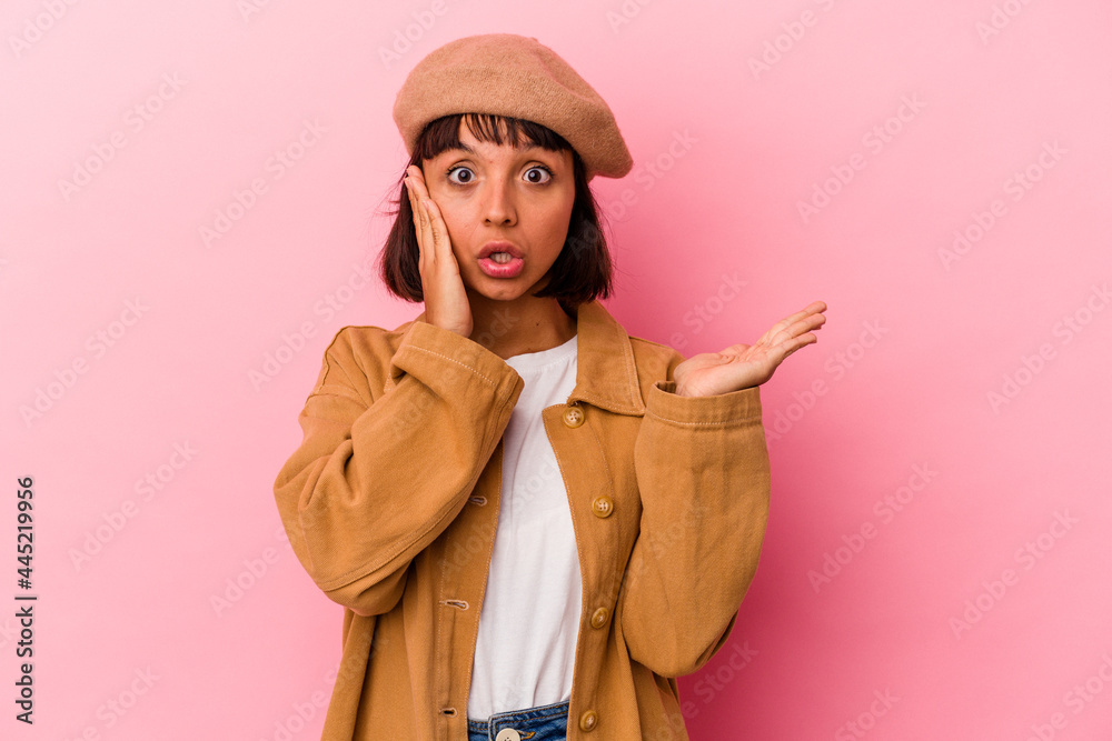 Young mixed race woman isolated on pink background impressed holding copy space on palm. Young mixed race woman isolated on pink background impressed holding copy space on palm.