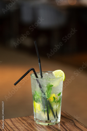 Refreshing summer cocktail mojito with ice, fresh mint and lime. Mojito cocktail on a dark background. Wooden stand.