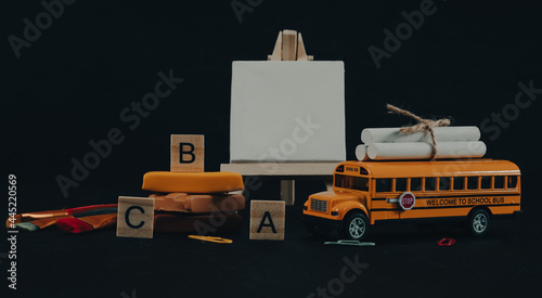 School bus and easel. School bus, easel, plasticine, brushes and wooden alphabet cubes on a black background, close-up side view.