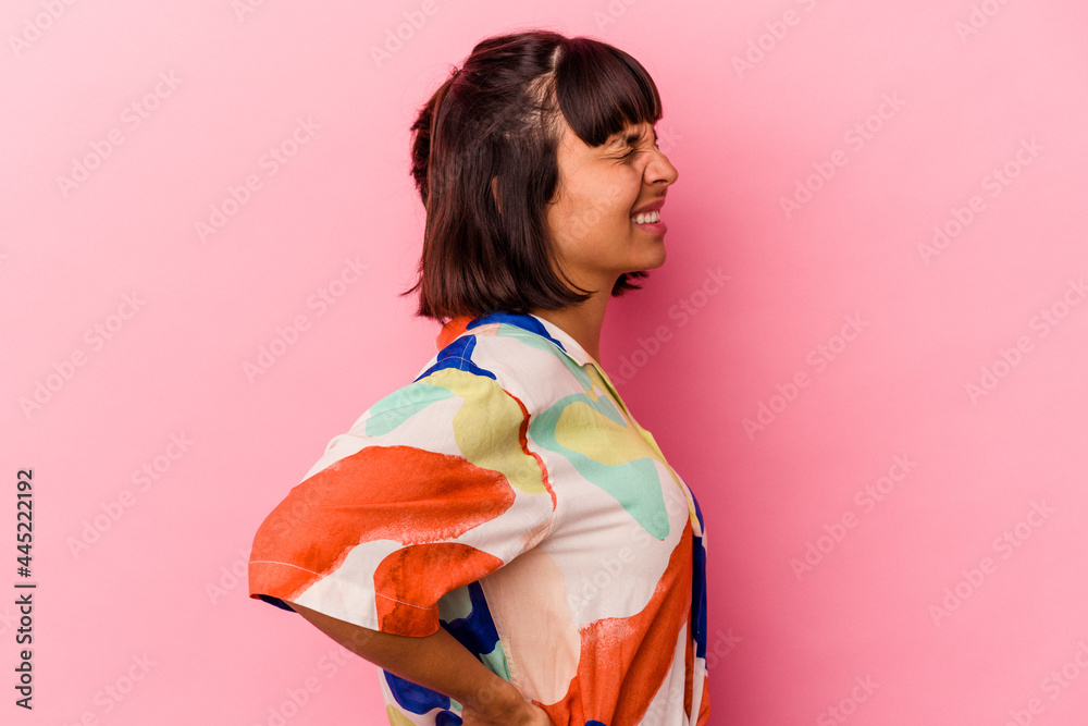 Young mixed race woman isolated on pink background suffering a back pain. Young mixed race woman isolated on pink background suffering a back pain.