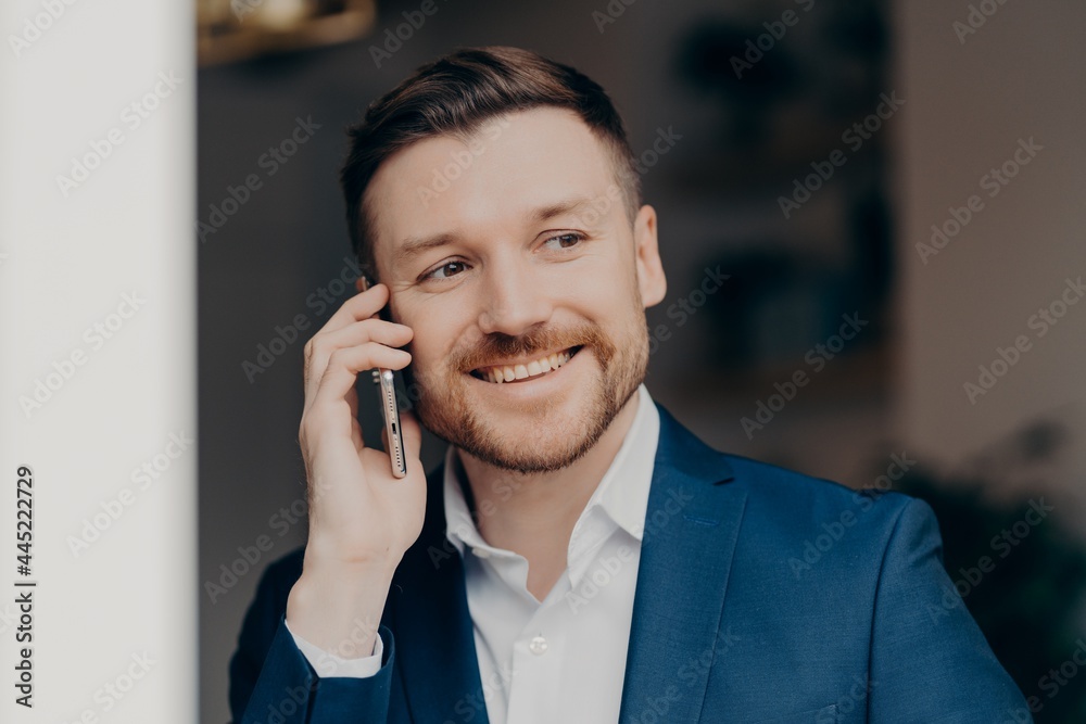 Smiling young man in suit using mobile phone at home Smiling young man in suit using mobile phone at home
