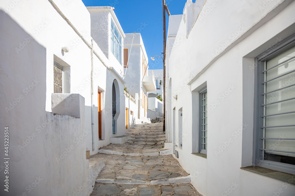 Whitewashed buildings cobblestone alley background at Sifnos island, Greece.