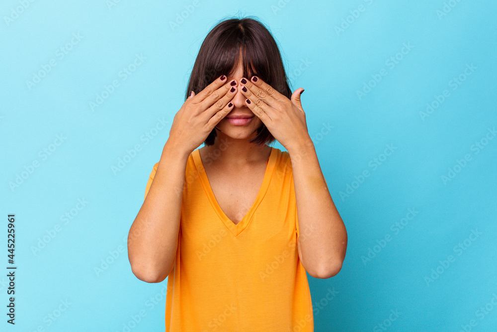 Young mixed race woman isolated on blue background afraid covering eyes with hands. Young mixed race woman isolated on blue background afraid covering eyes with hands.