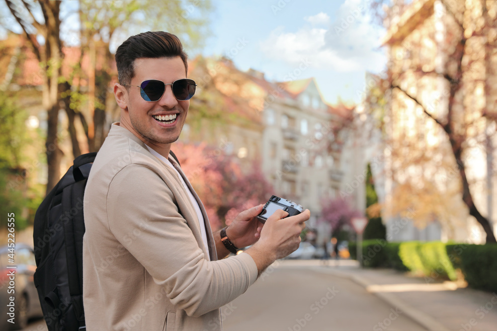 Fototapeta premium Happy male tourist with camera on city street