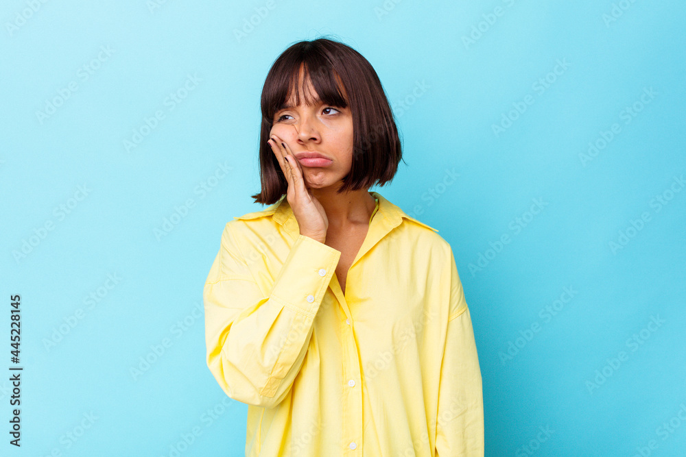 Young mixed race woman isolated on blue background tired and very sleepy keeping hand on head. Young mixed race woman isolated on blue background tired and very sleepy keeping hand on head.
