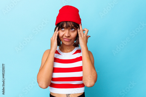 Young mixed race woman isolated on blue background having a head ache, touching front of the face.