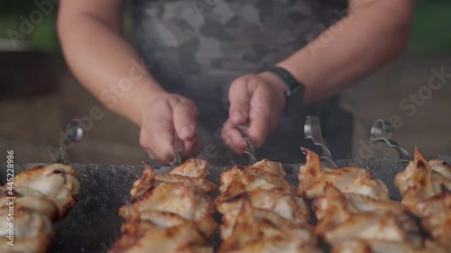 Man coocing chicken wings on a skewers. Hd slowmotion closeup shot with shallow dof photo