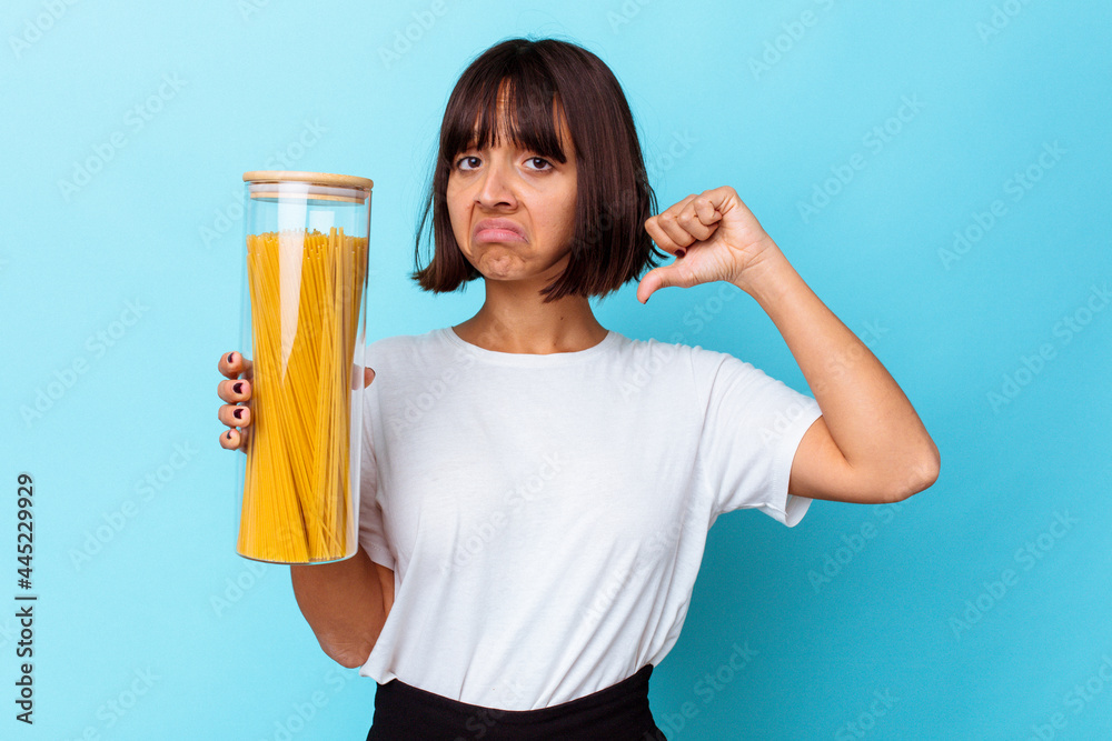 Young mixed race woman holding pasta jar isolated on blue background feels proud and self confident, example to follow. Young mixed race woman holding pasta jar isolated on blue background feels proud and self confident, example to follow.