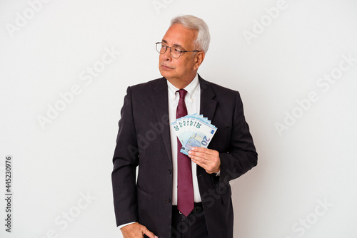 Senior american business man holding bills isolated on white background confused, feels doubtful and unsure.