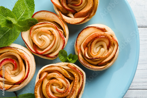 Freshly baked apple roses on white wooden table, top view. Beautiful dessert