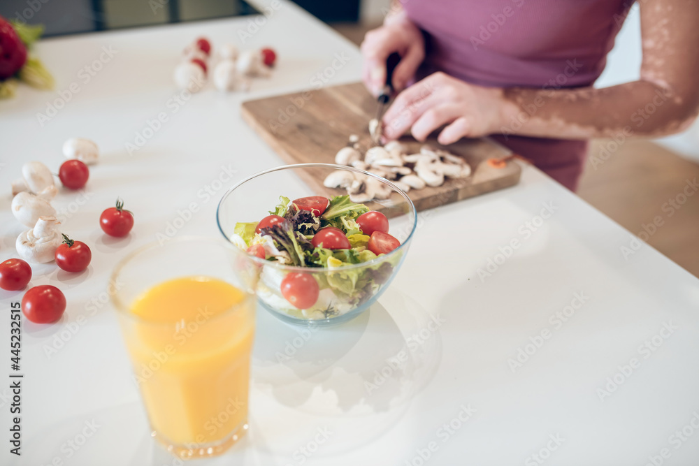 A dark-skinned woman cooking in the kitchen and cutting vegetables
